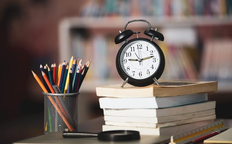 book-laptop-pencil-clock-wooden-table-library-education-learning-concept_1150-16628
